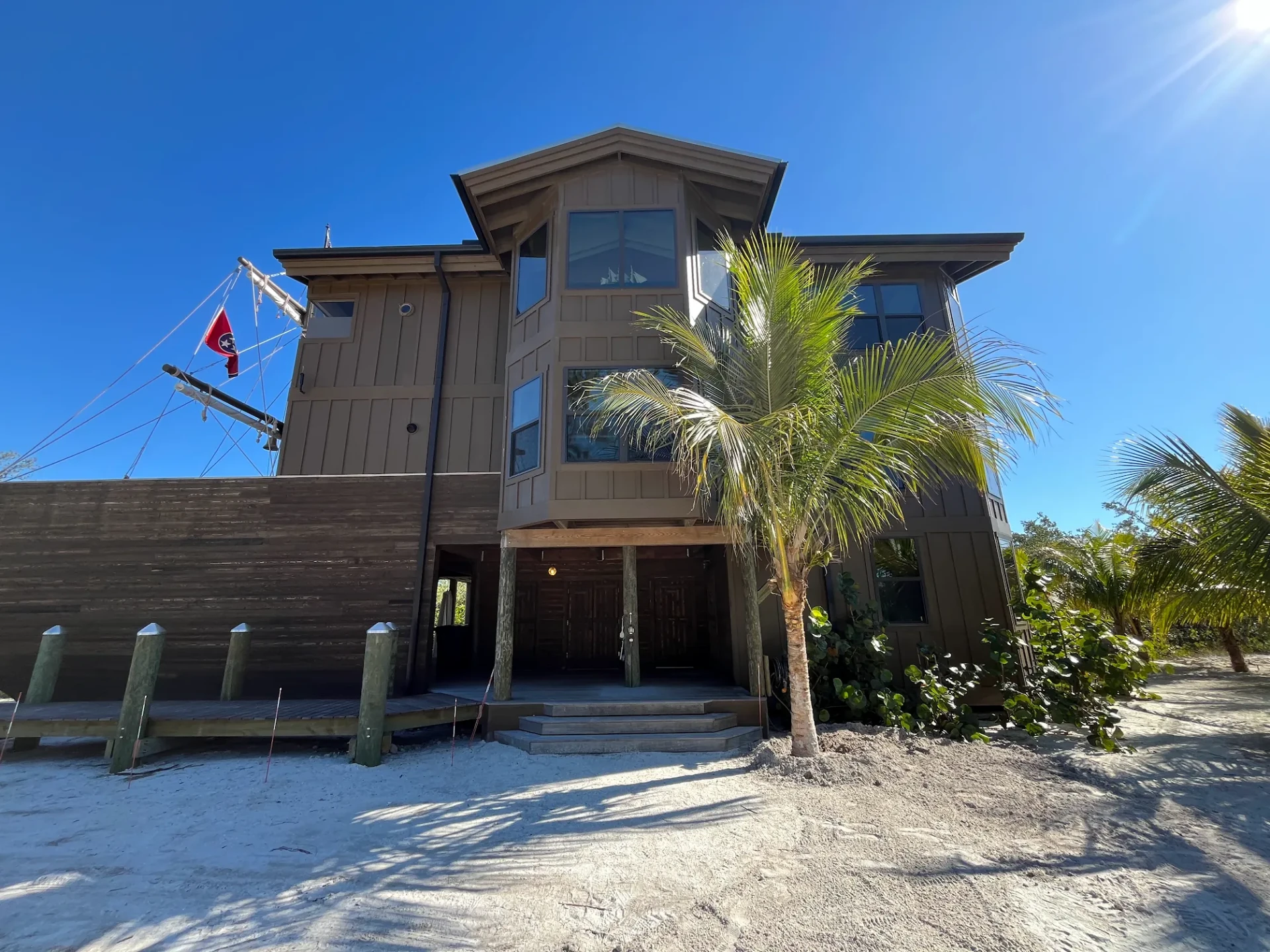 The Ship House on Jewfish Key, a coastal elevated home with palm trees and bright blue sky